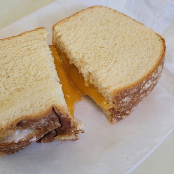 A grilled cheese sandwich cut in half, revealing melted orange cheese oozing out.