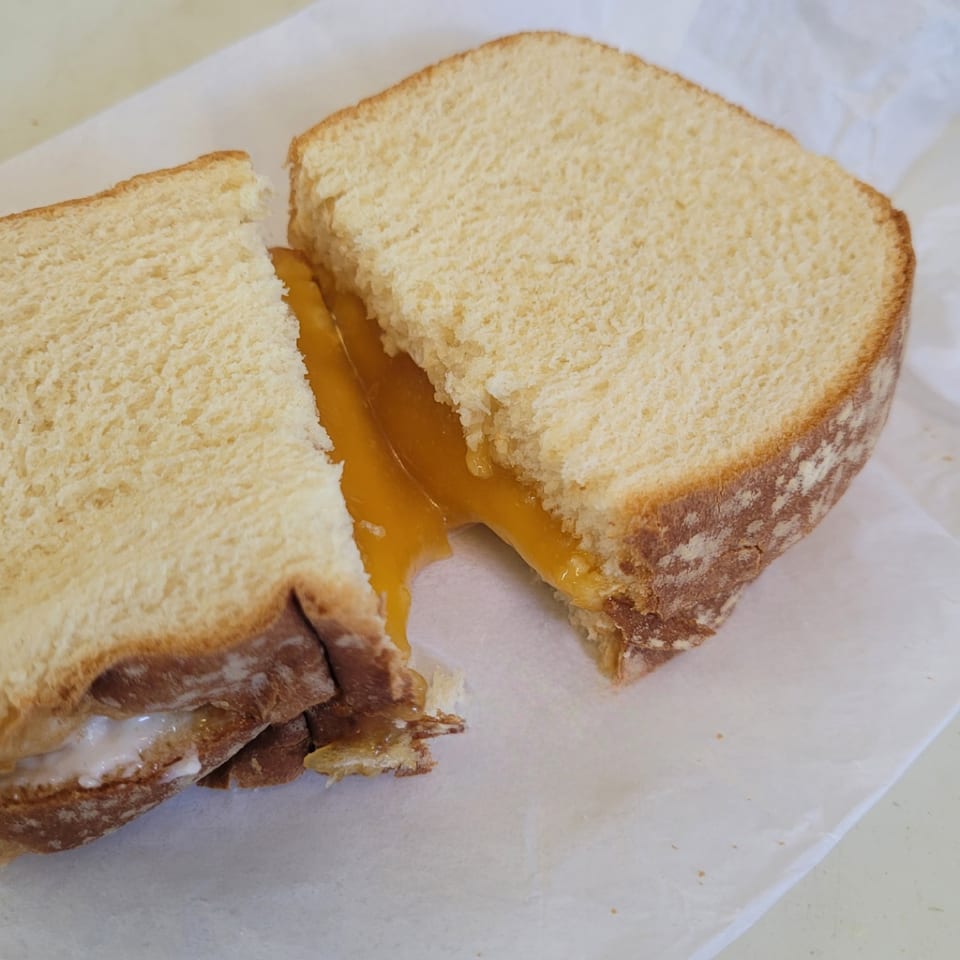 A grilled cheese sandwich cut in half, revealing melted orange cheese oozing out.