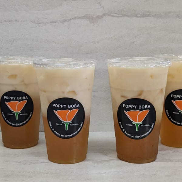 Four Poppy Boba drinks with two-toned liquid, featuring the brand's poppy logo on each cup.